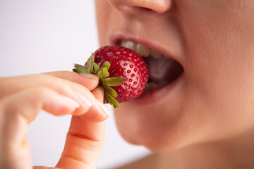 Closeup of a woman's mouth eating a strawberry. Concept of allergy on a strawberry. 