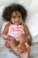 Little african american girl child with curly hair in bed looking at camera