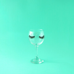 Glass cup with lashes. Celebration. Female party. Turquoise background.