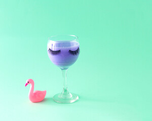Glass with lashes and flamingo. Celebration. Female party. Turquoise background.