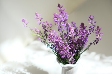 Bouquet of purple wild flowers field bell flowers in white vase on white shelf in the bathroom. The...