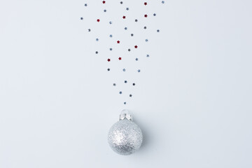 Christmas grey minimal background with grey ball and confetti. Flat lay, copy space