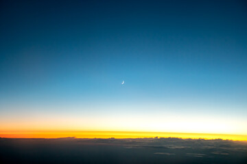 Sunset and the moon over the clouds outside my airplane window at 32,000 feet.