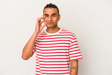 Young venezuelan man isolated on white background with fingers on lips keeping a secret.