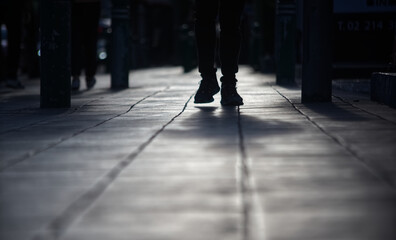 A person silhouette is walking on a sidewalk