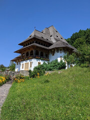 Fototapeta na wymiar Rustic Barsana monastery with garden and blue sky