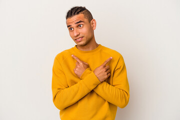 Young venezuelan man isolated on white background points sideways, is trying to choose between two options.
