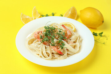 Plate of tasty shrimp pasta on yellow background