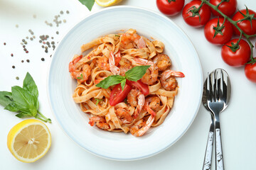 Plate of shrimp pasta and ingredients on white background