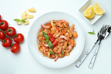 Plate of shrimp pasta and ingredients on white background