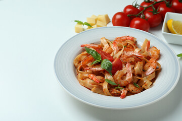 Plate of shrimp pasta and ingredients on white background