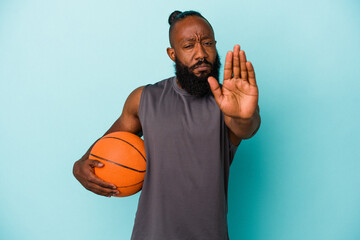 African american man playing basketball isolated on blue background standing with outstretched hand...