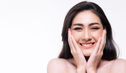 Smiling young woman isolated on white background. Asian happy girl touching her face with clean fresh skin while looking at camera. Healthy skin care concept.