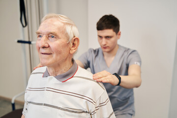 Manual therapist setting senior man in straight position