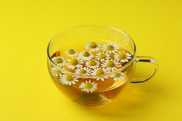 Cup of chamomile tea on yellow background