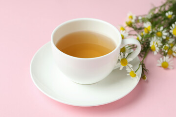 Cup of chamomile tea on pink background