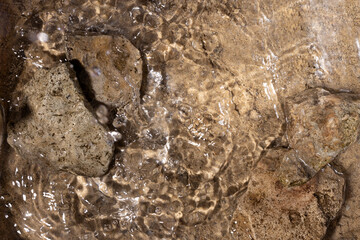 Top view of brown sand and stones in the water,waves.Empty space for design or product