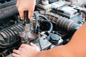 Car repair. Auto mechanic working on car engine in mechanics garage. Repair service. Close up of...