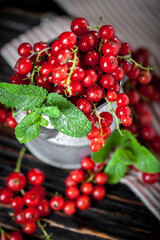 Ripe red currant berries in a bowl. Fresh red currants on dark rustic wooden table. Background with copy space. Selective focus.