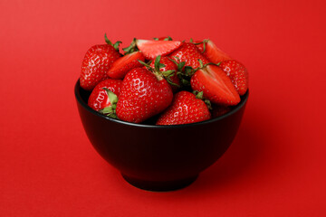 Bowl of fresh strawberry on red background