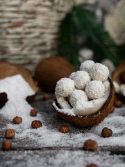 Coconut candy, balls, coconuts and hazelnuts on a rustic wooden surface