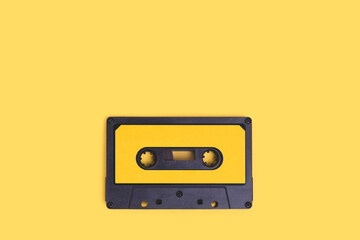 Obraz premium Cassette tape on a yellow background with copy space.