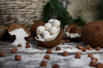 Coconut candy, balls, coconuts and hazelnuts on a rustic wooden surface