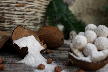 Coconut candy, balls, coconuts and hazelnuts on a rustic wooden surface