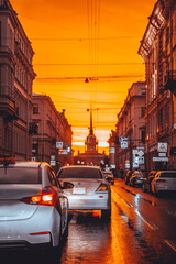 The Admiralty Tower was photographed in a stream of cars at a bright red sunset. Saint Petersburg, Russia - 28 June 2021