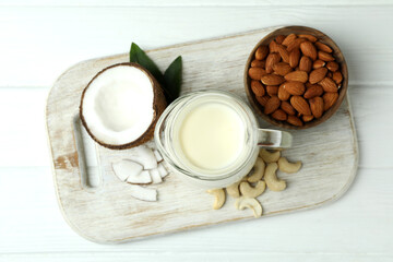 Concept of vegan milk on white wooden background, top view