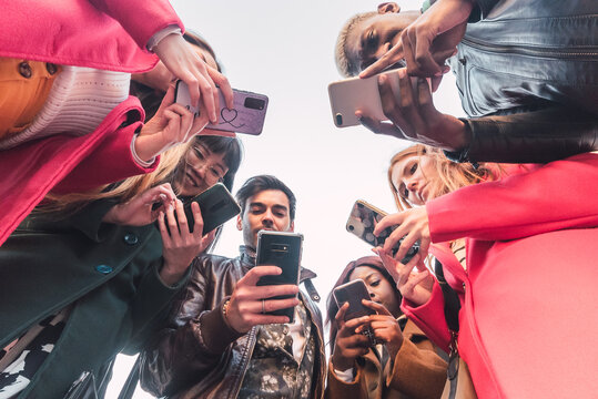 Company of diverse people using smartphones in street