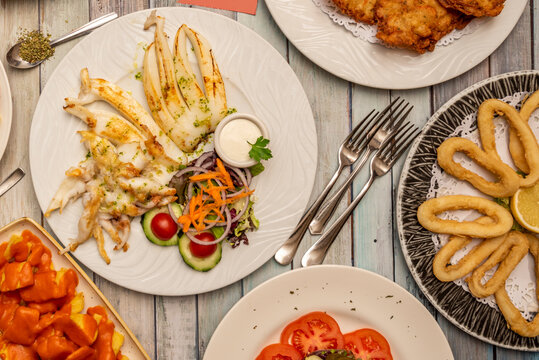 Typical tapas restaurant dishes, grilled cuttlefish, Roman squid, scrambled eggs with ham, cod croquettes, patatas bravas.