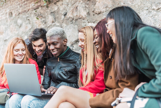 Group of multiracial friends gathering around laptop