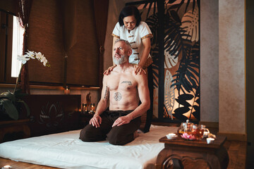 Fototapeta na wymiar Smiling lean tatooed male enjoying thai massage