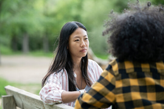 Lesbian couple of multiethnic women holding hands near lake