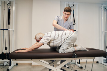 Elderly patient in prone position undergoing treatment from therapist