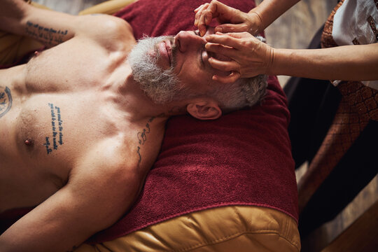 Handsome grizzled man during asian face massage