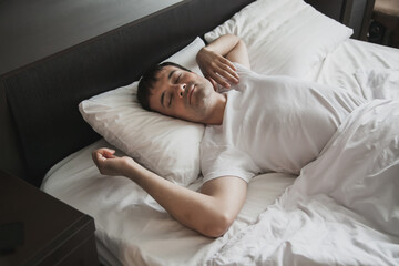 A middle-aged man in bed in his bedroom wakes up in the morning with a smile on his face. The concept of healthy sleep