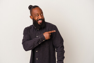 African american man with beard isolated on pink background points with thumb finger away, laughing and carefree.