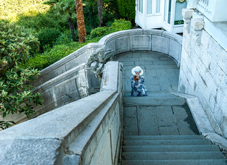 A girl is sitting on the stairs of the royal palace in Livadia. Yalta, Crimea.