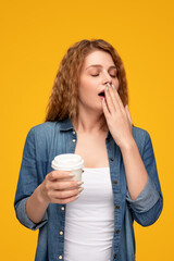 Yawning woman with takeaway coffee