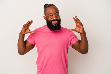 African american man with beard isolated on pink background holding something with palms, offering to camera.