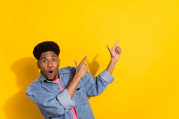 Fototapeta premium Photo of amazed shocked dark skin young man point finger empty space news isolated on yellow color background