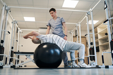 Senior male doing back exercise on fitness ball