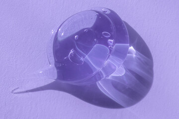 Glycerin or gel smear smudge swatch on lilac backdrop with shadow. Cosmetic product closeup texture...