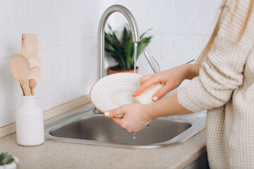 Woman washes dishes by eco brush.Zero waste - obrazy, fototapety, plakaty