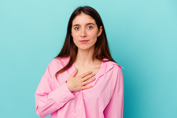 Young caucasian woman isolated on blue background taking an oath, putting hand on chest.