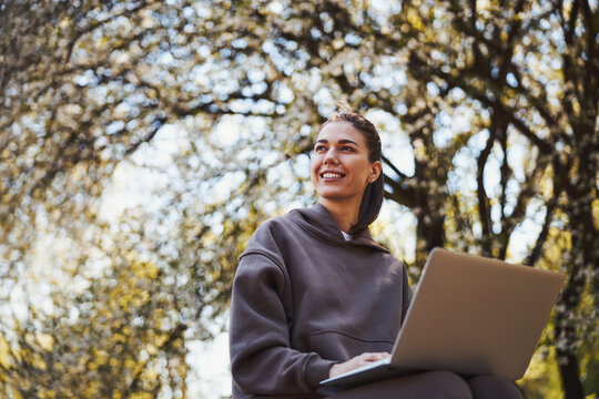 Positive woman is working with laptop outdoors