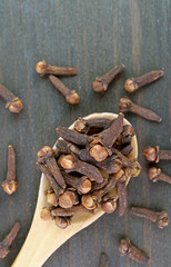 Top View of Dried Cloves on Wooden Spoon with Some Scattered on the Background