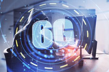 Hacker in hoodie using computer with glowing 6G interface in blurry office interior. Hacking, theft and communication concept. Double exposure.